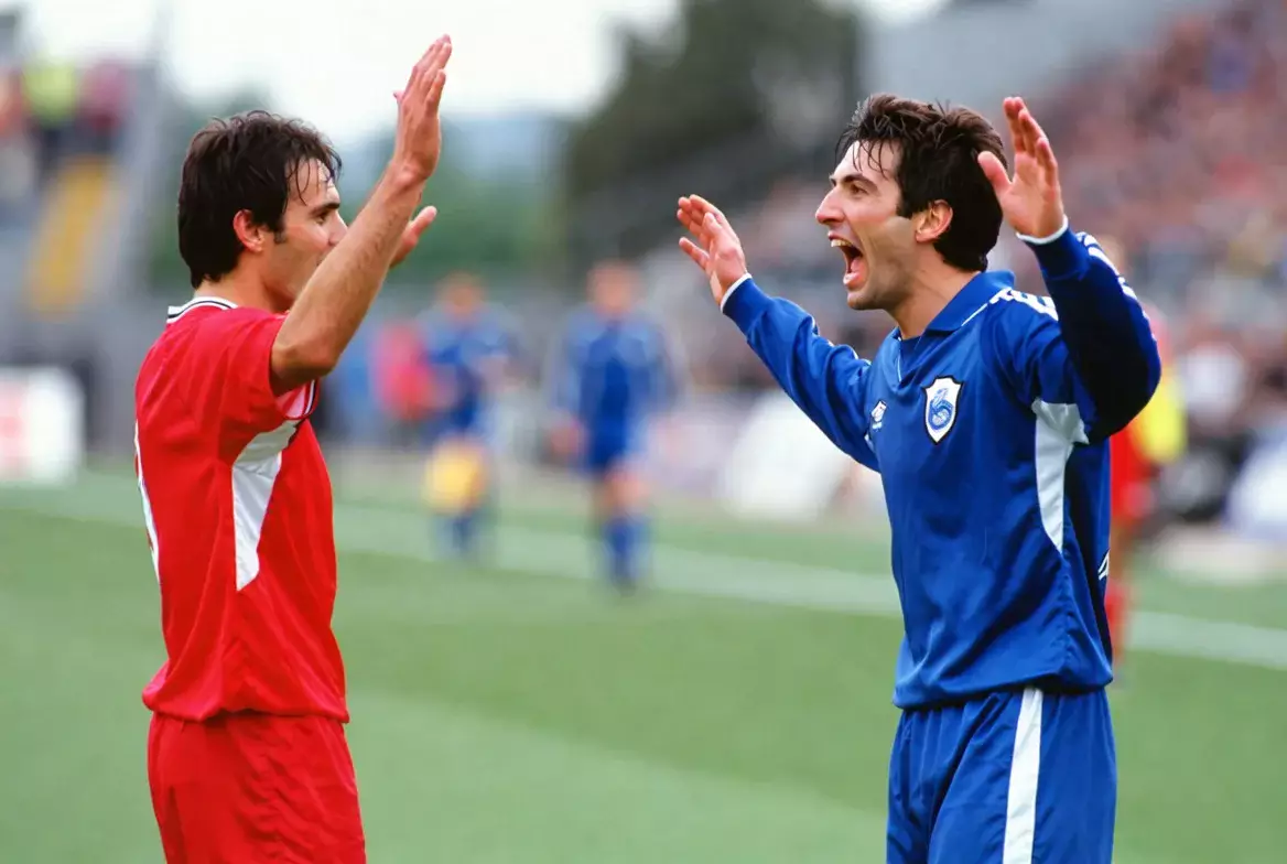 Due calciatori di squadre diverse che esultano dopo aver segnato